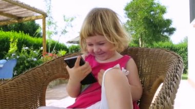 Bebek hasır koltuğunda oturmak telefon izlerken