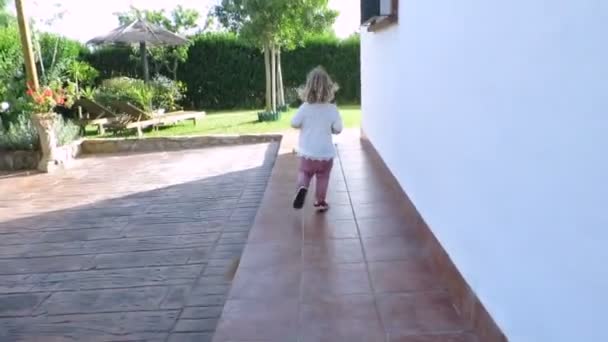 Blonde baby loopt van huis deur naar tuin Slowmotion — Stockvideo