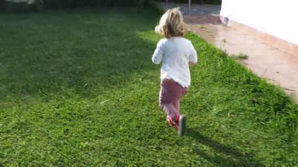 Bebê loiro correndo no jardim câmera lenta — Vídeo de Stock