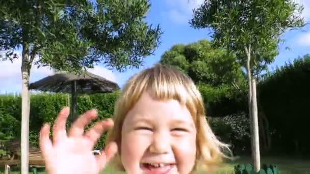 Blonde happy baby spelen achter camera in tuin — Stockvideo