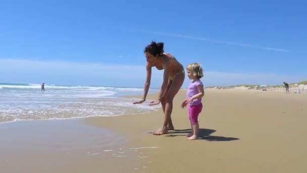 Piccolo bambino e madre in spiaggia con onde — Video Stock