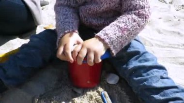 kum plajı üzerinde oturan demet taşlarla oynayan bebek