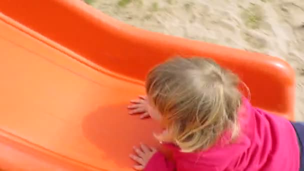 Bebê brincando em slide laranja — Vídeo de Stock
