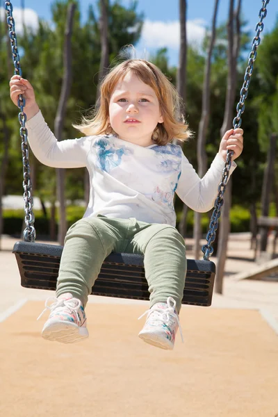 Little kid swinging at urban park — Stock Photo, Image