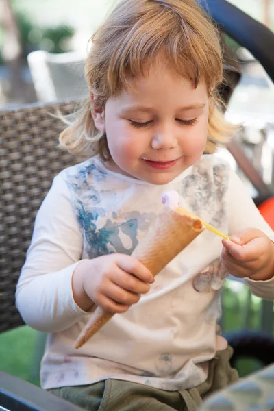 Šťastné dítě jíst zmrzlinu kužel s lžící — Stock fotografie