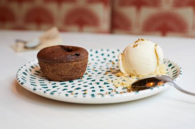 Çikolata bir kepçe vanilyalı dondurma ile güzel bir seramik tabakta kaşıkla, bir restoran masasının beyaz masa örtüsünün üzerinde