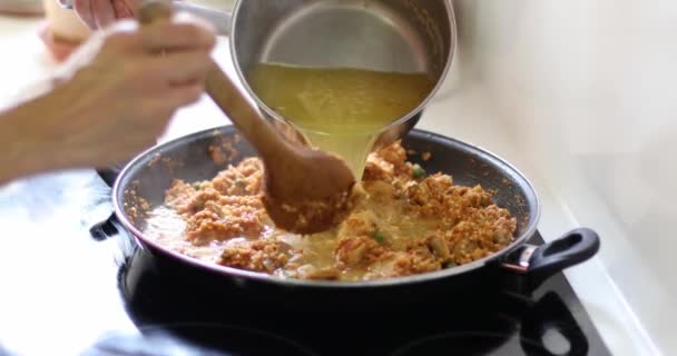 Woman Hands Pouring Broth Paella Pan Rice Chicken Vegetables Stirring — Stock Video