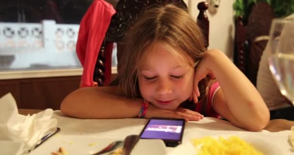 レストランでの幸せな顔をしたスマートフォンを使った6歳のかわいい子供の肖像画 — ストック動画