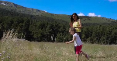 4k video. Dört yaşındaki sarışın kadın ve kızı Madrid, İspanya ve Avrupa yakınlarındaki Guadarrama dağlarında çiçeklerle çayırlarda yürüyorlar.