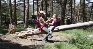 Yedi yaşında, Guadarrama Doğal Parkı 'nda (Madrid, İspanya) çam ağacının gövdesinde oturan ve elleriyle oynayan çocuk ve kadın.)