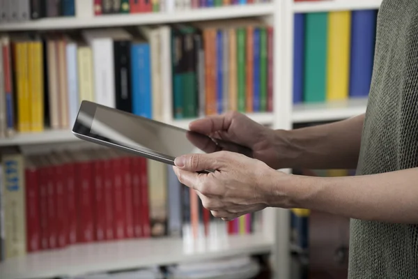 Tablet in handen bij bibliotheek — Stockfoto