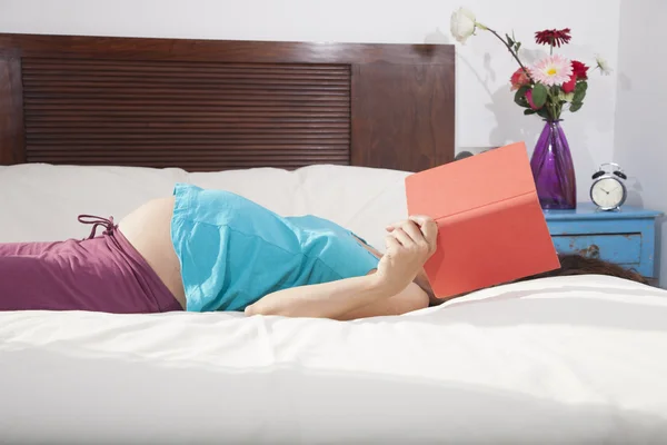 Pregnant reading lying in bed — Stock Photo, Image