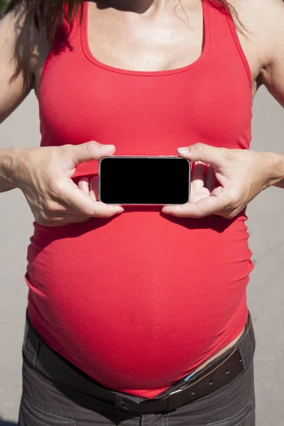 Pantalla del teléfono inteligente en la barriga mujer embarazada — Foto de Stock