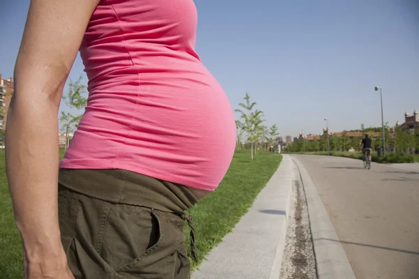 Vientre rosa embarazada en parque — Foto de Stock