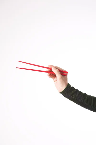 Красные палочки для еды в руке женщины — стоковое фото