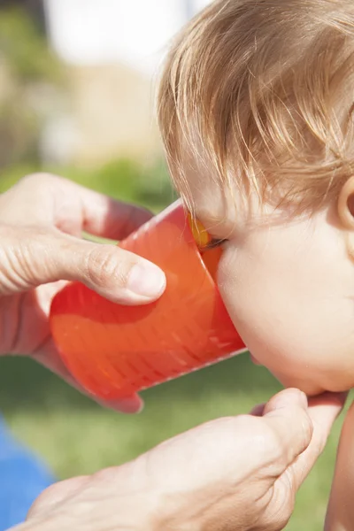 Baby drinking orange cup — Stock Photo, Image