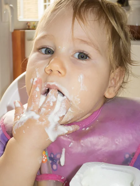 Baby eten yoghurt met haar hand — Stockfoto