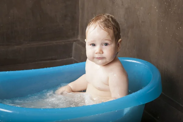 Wet baby bathing looking in blue little bath indoor — Stock Photo, Image