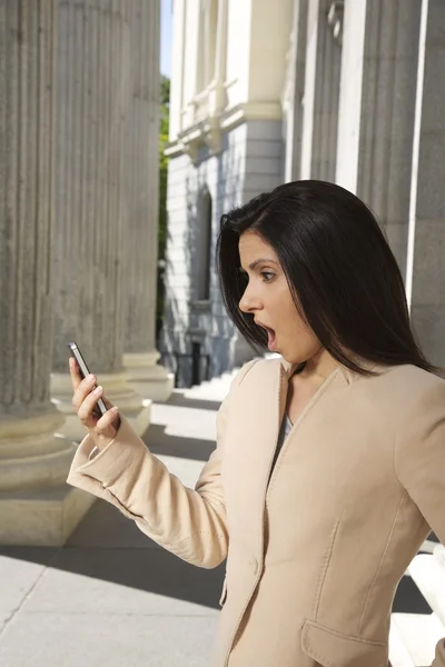 Chockad affärskvinna på smartphone — Stockfoto