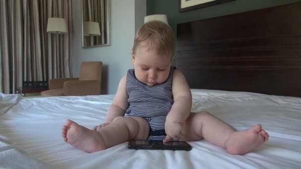 Bébé avec smartphone au lit — Video