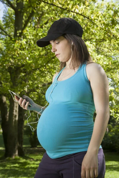 Gravid lyssna med hörlurar — Stockfoto