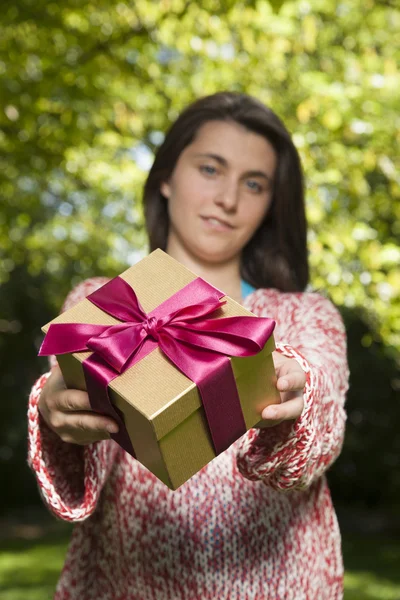 Red and golden gift in young hands — Stock Photo, Image