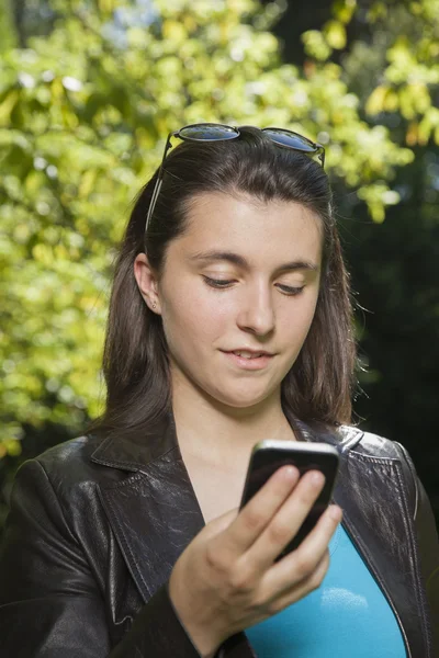 Junge Frau schaut aufs Smartphone — Stockfoto