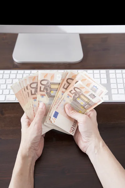 Counting Euros banknotes on computer — Stock Photo, Image