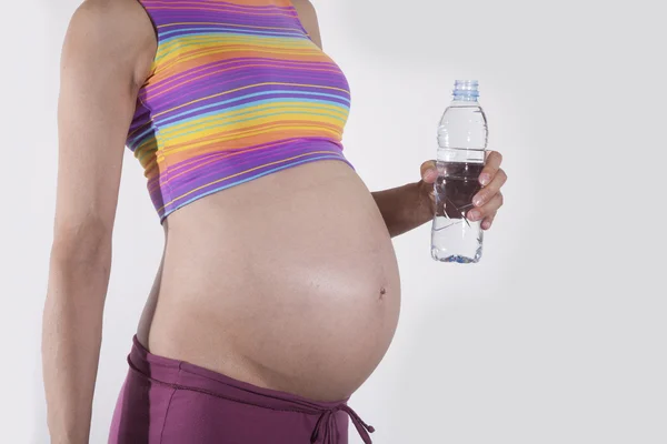 Schwangerer Bauch mit Wasserflasche — Stockfoto