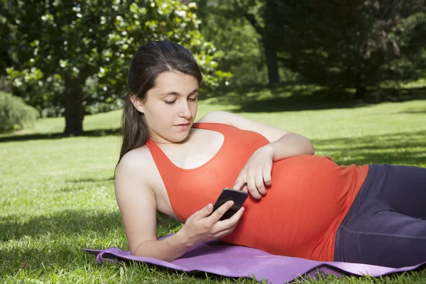 Schwanger mit Smartphone liegen — Stockfoto