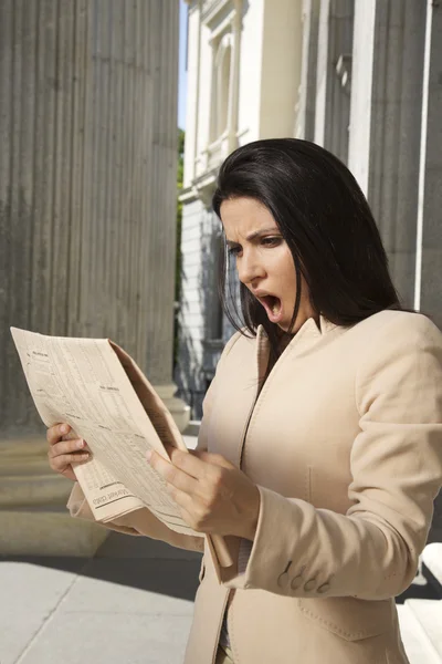 Shocked businesswoman reading newspaper — Stock Photo, Image