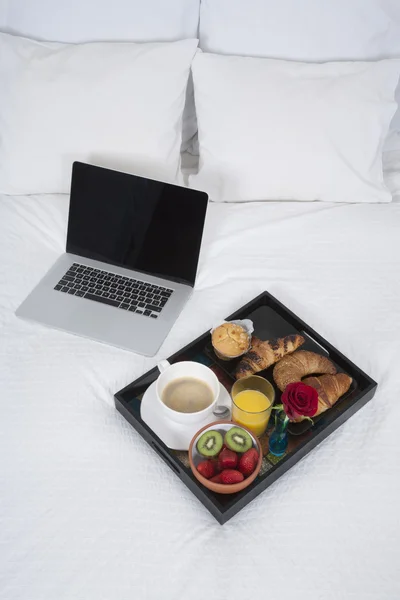 Ontbijt en laptop op bed — Stockfoto