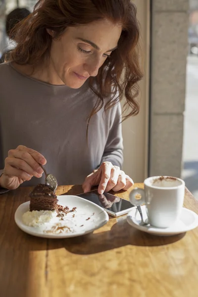 Woman chocolate cake and phone — Stock Photo, Image