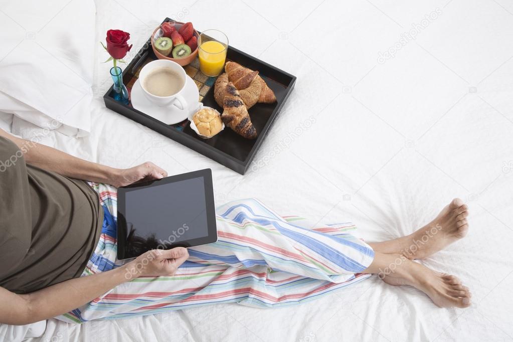 woman bed tablet breakfast