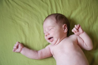 baby newborn crying on green sheet