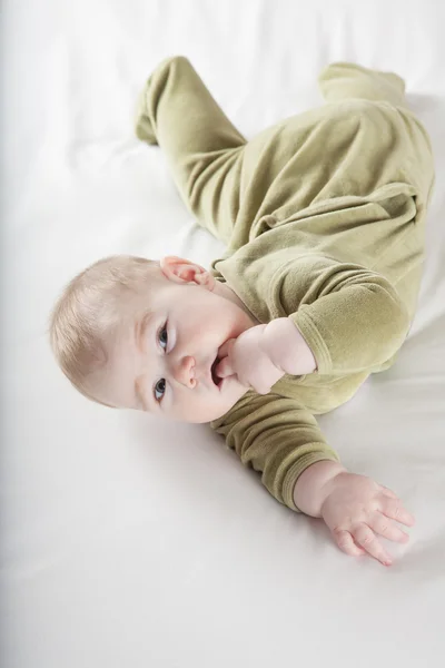 Baby lying twisted looking at camera — Stock Photo, Image