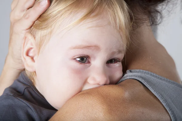 Lágrimas en los ojos del bebé abrazado madre Imagen de stock