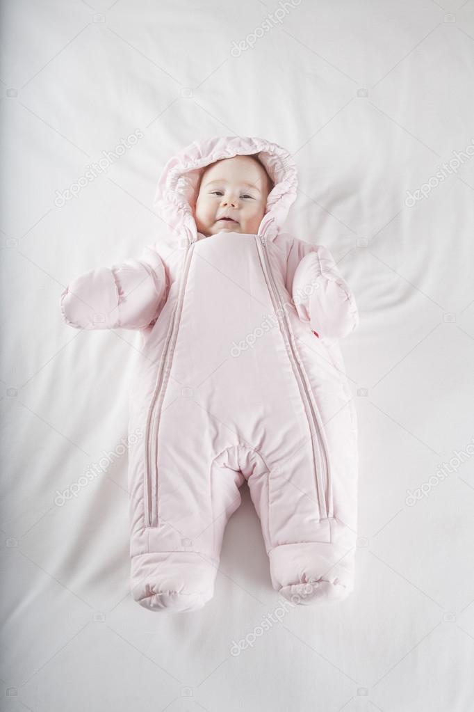 pink snowsuit baby on bed