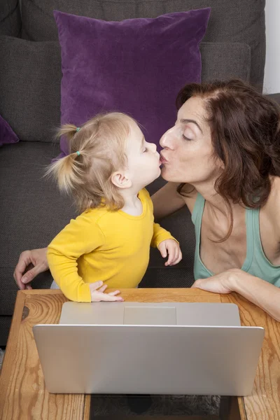 Baby and mom kissing with laptop — Stock Photo, Image