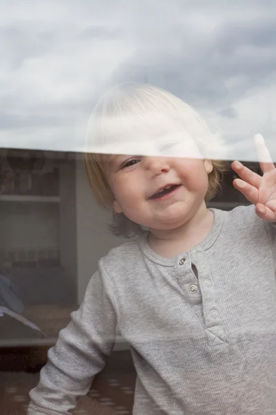 Baby saluting through glass — Stock Photo, Image