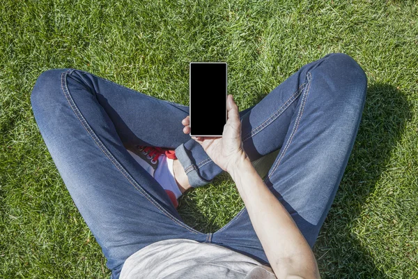 Leere Bildschirmtelefon mit Beinen auf Gras — Stockfoto