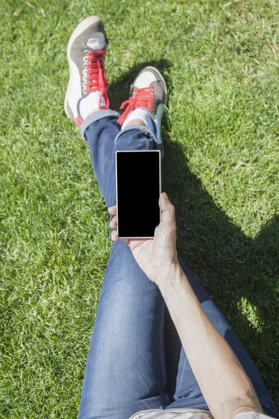 Phone in hand legged on grass — Stock Photo, Image