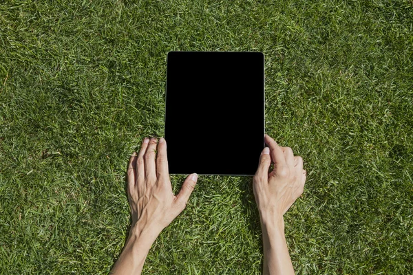 Руки з планшетом на траві — стокове фото