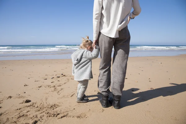 Baby and mother holding hands next to ocean — Stockfoto