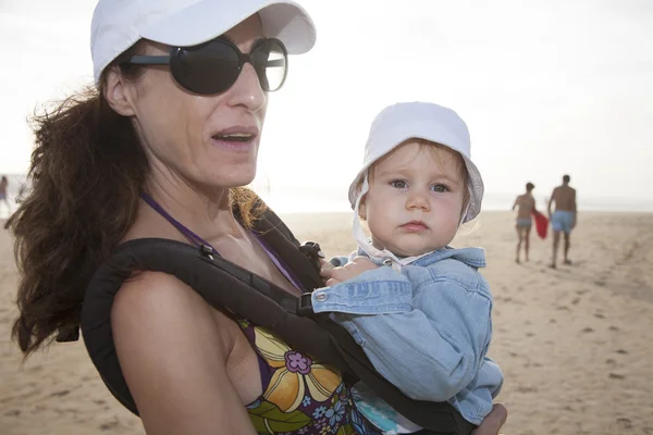 Maman et bébé dans le sac à dos à la plage — Photo
