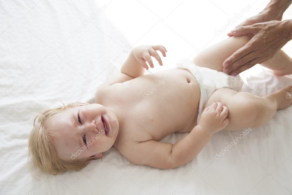 Download - One year blonde baby naked crying over white bedcover with mom a...