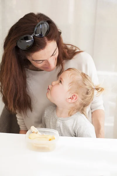 Bebê comendo e olhando mãe — Fotografia de Stock