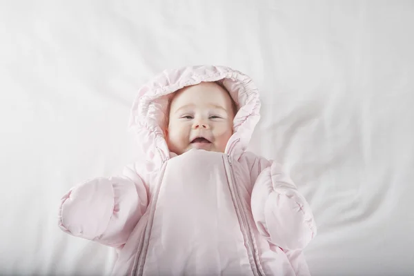 Sonriente cara de bebé envuelta en traje de nieve rosa — Foto de Stock