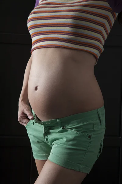 Gravid kvinna på mörk bakgrund — Stockfoto