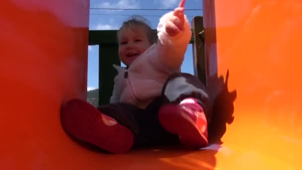 Счастливый ребенок в оранжевой горке — стоковое видео